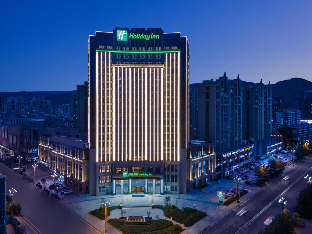 Holiday Inn Xining Datong, an IHG Hotel في شينينغ: مبنى مضاء في مدينة في الليل