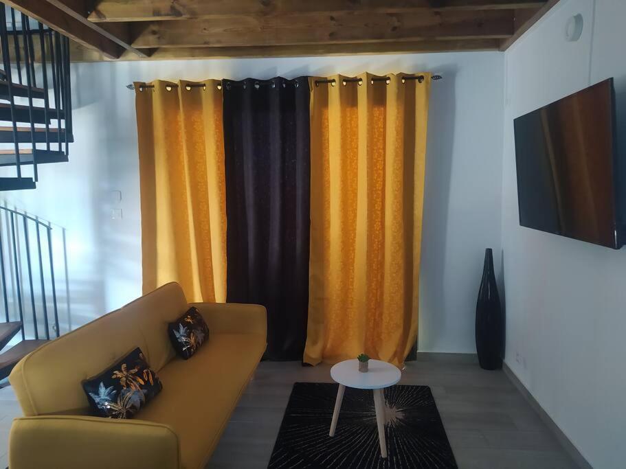 a living room with yellow and black curtains and a couch at Le coin paisible in Saint-Louis