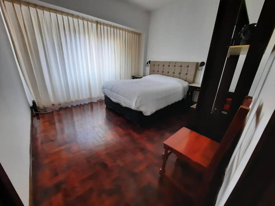 een slaapkamer met een wit bed en een houten vloer bij Hermoso Departamento centrico in Cordoba