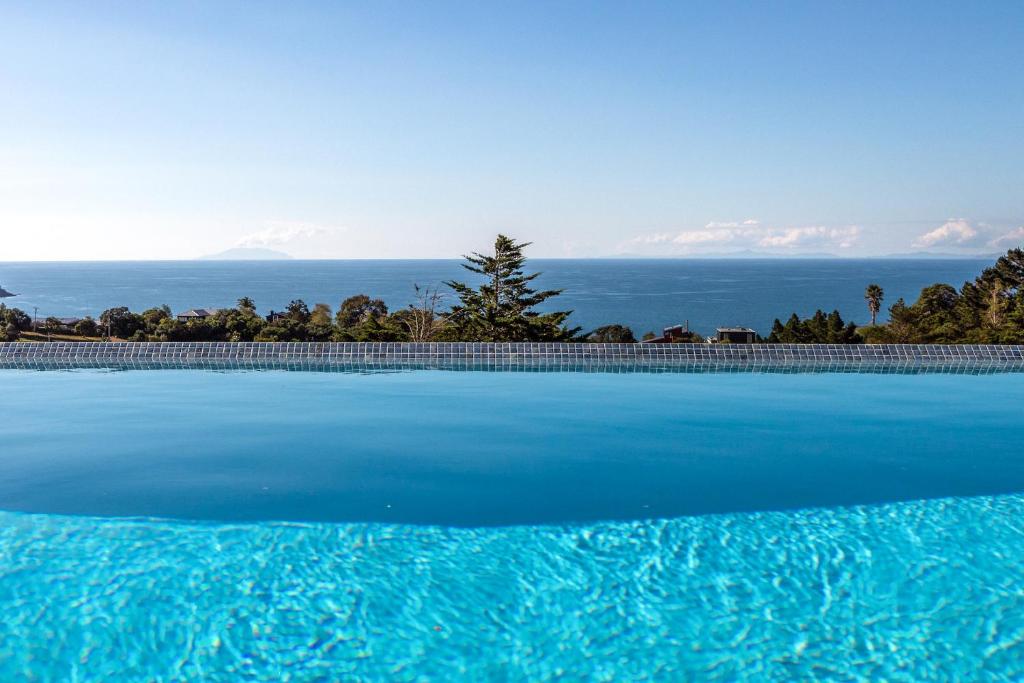 a large swimming pool with a view of the ocean at The Villino at Cypress Ridge Estate in Onetangi