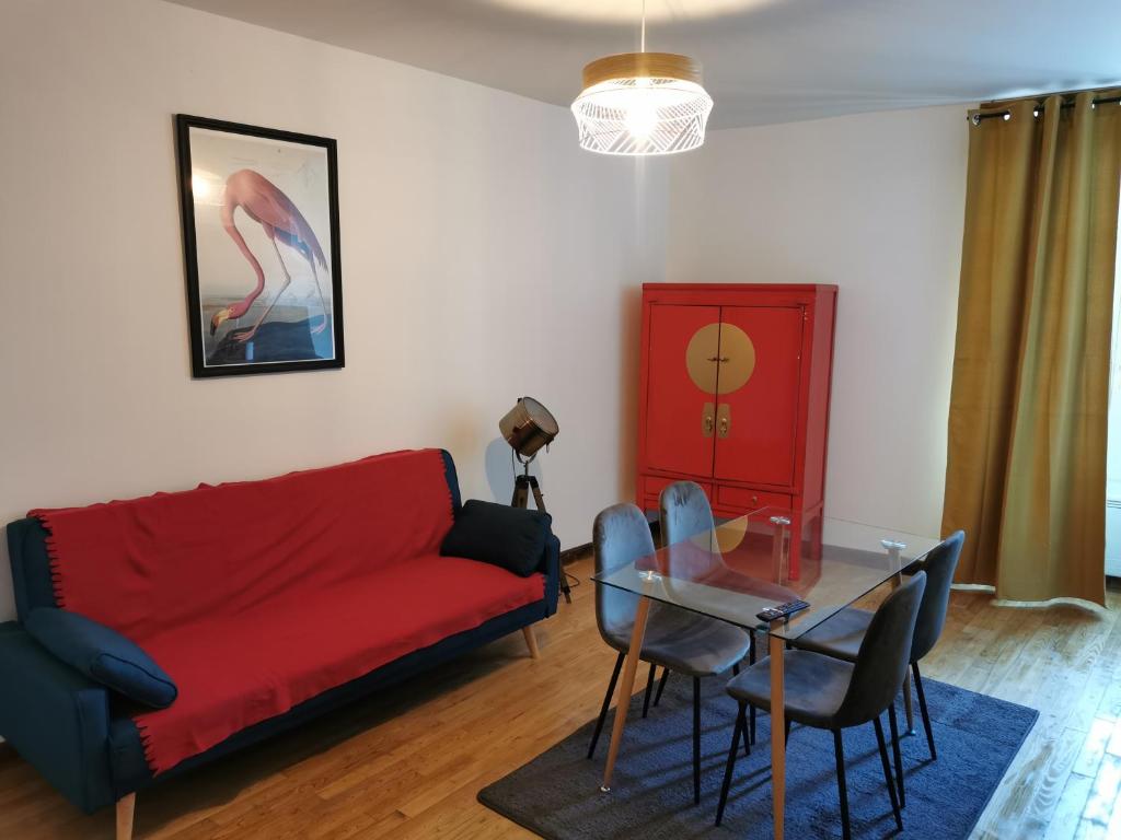 a living room with a red couch and a glass table at Centre Confolens studios rénovés in Confolens