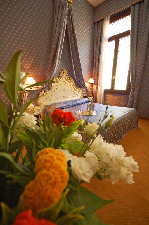 a bedroom with a bed with flowers in the foreground at Hotel Torino in Venice