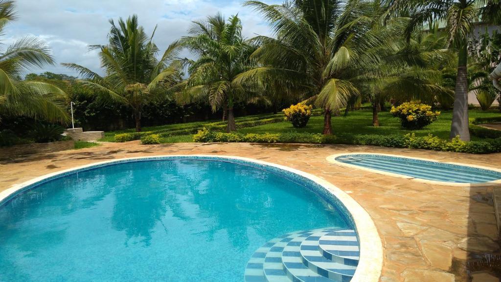 a swimming pool in a yard with palm trees at Galu Gardens Apartments Diani Beach in Diani Beach