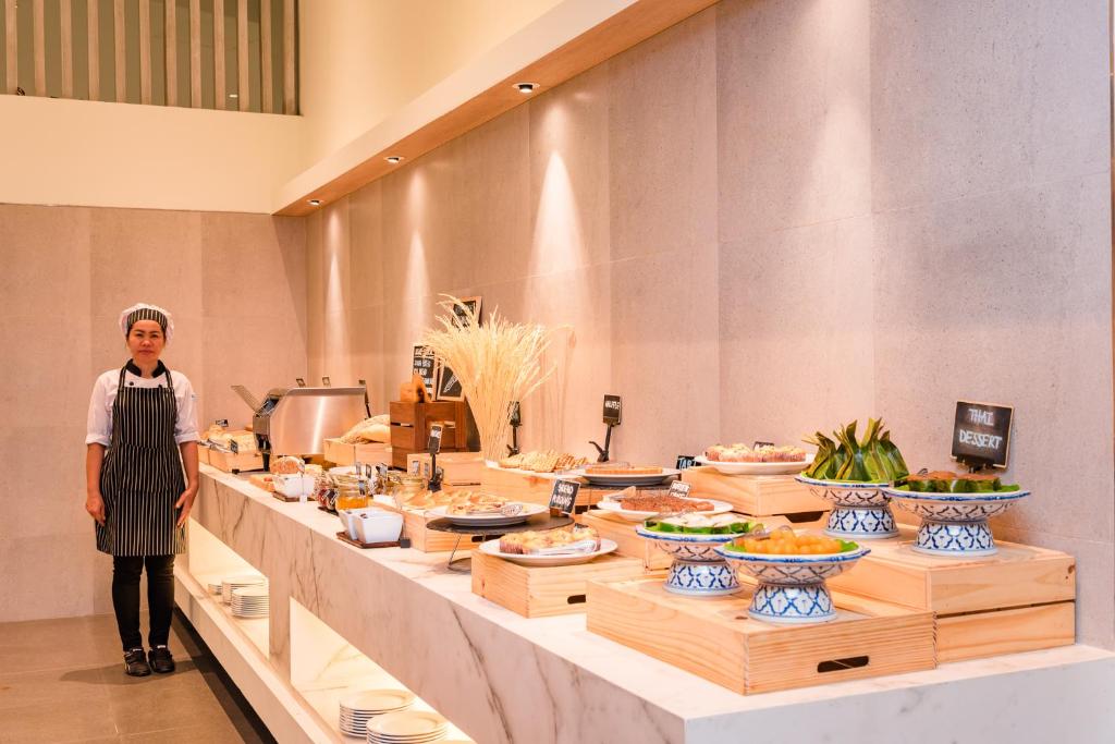 a woman standing in front of a buffet line with food at Oceanfront Beach Resort - SHA Extra Plus in Patong Beach