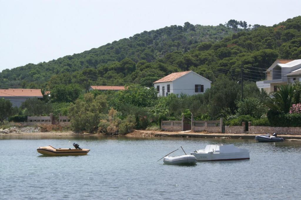 three boats on a lake with houses and trees at Apartments by the sea Vrgada, Biograd - 4206 in Biograd na Moru