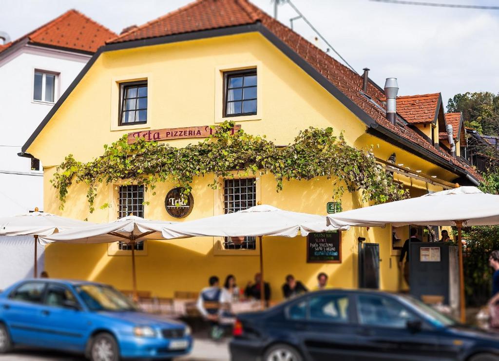 a yellow building with umbrellas and cars parked in front of it at House Trta in Ljubljana
