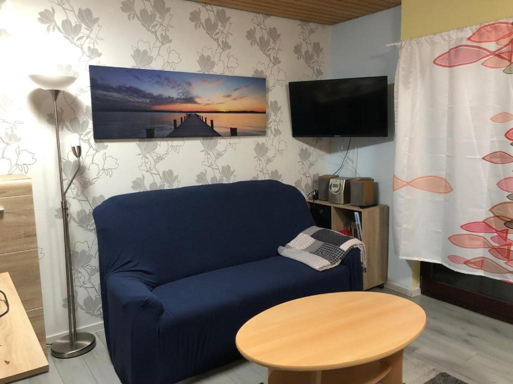 uma sala de estar com um sofá azul e uma mesa em Ferienwohnung "Roter Sand" em Burhave