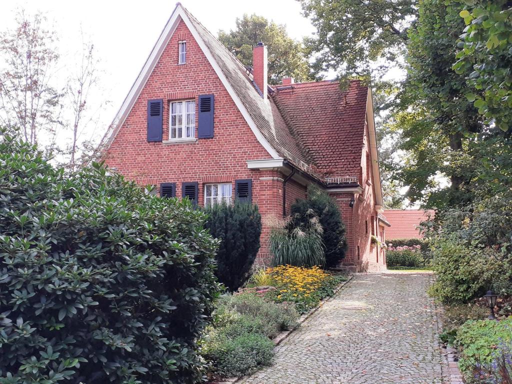 a red brick house with blue shutters and a driveway at Ferienwohnung Erika in Moritzburg