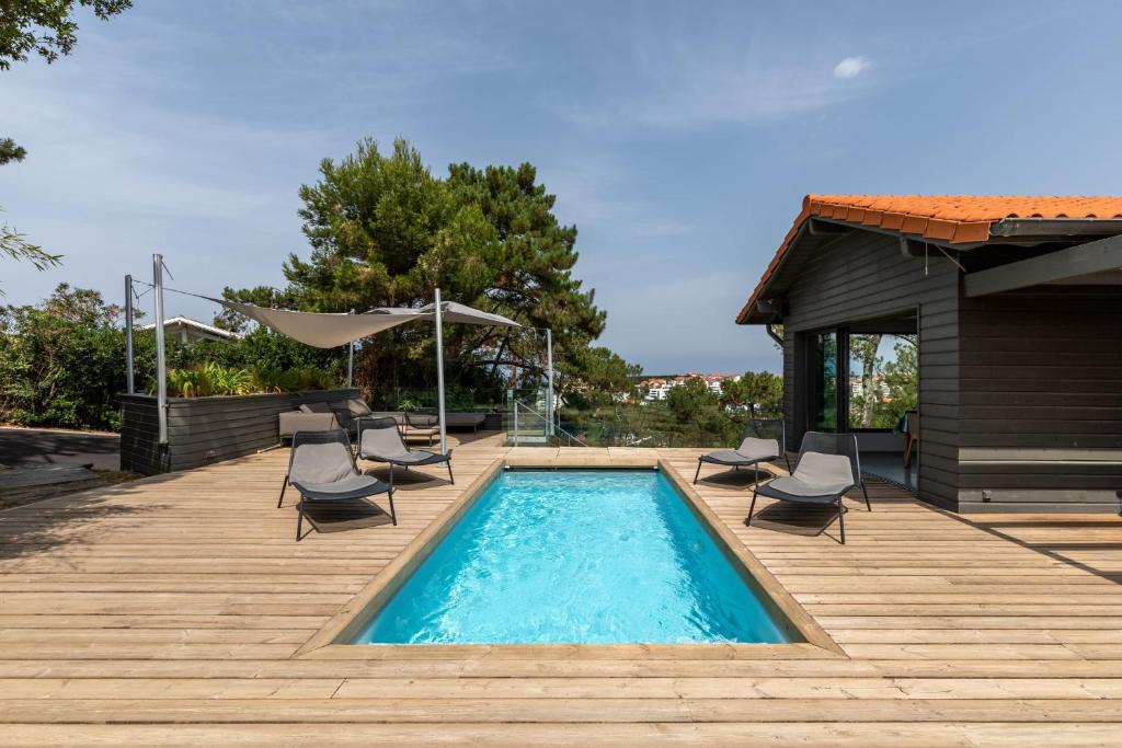 a swimming pool on a wooden deck with chairs at MILADY KEYWEEK Villa with Pool Ocean Views in Biarritz in Biarritz