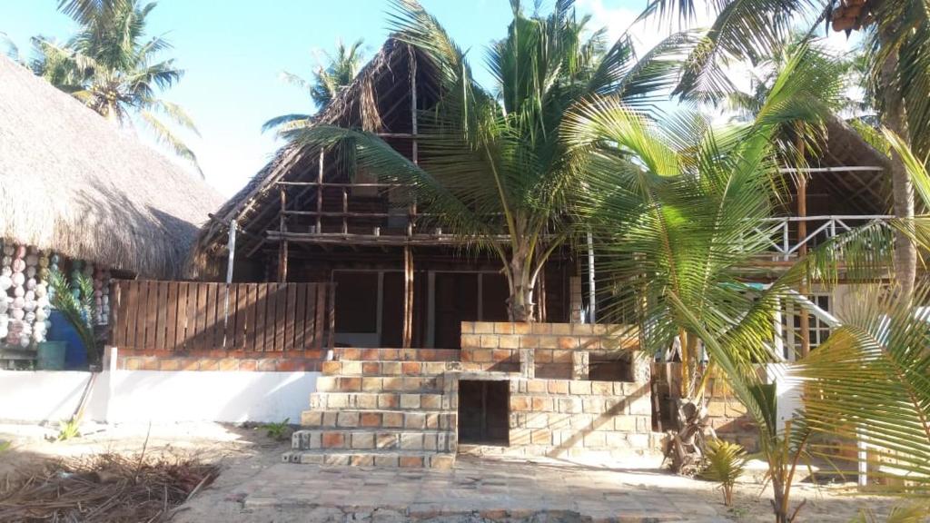 a house with a palm tree in front of it at Casa Coco Palmeira in Inhambane