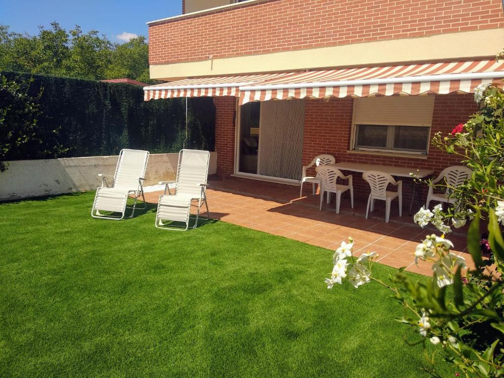 a backyard with chairs and a table and a patio at EL JARDIN DE LOS MANANTIALES in Castañares de Rioja