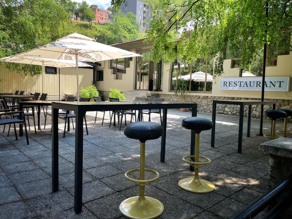 a table with two stools and an umbrella on a patio at Hotel Fersped in Mavrovo