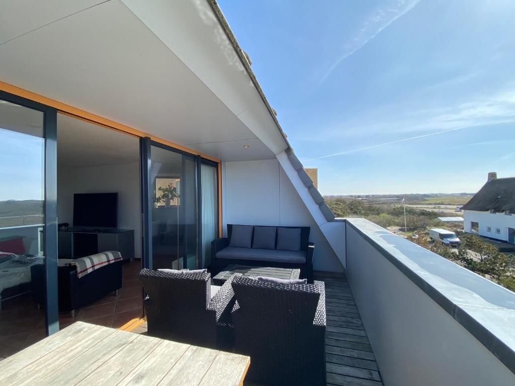 een balkon met een bank en een tafel en stoelen bij Callantsoger Staete A304 in Callantsoog