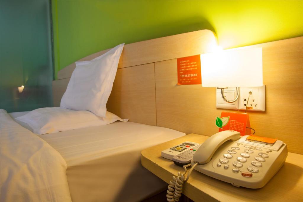 a hotel room with a phone and a bed at 7Days Inn East Street Dachashi Branch in Xi'an