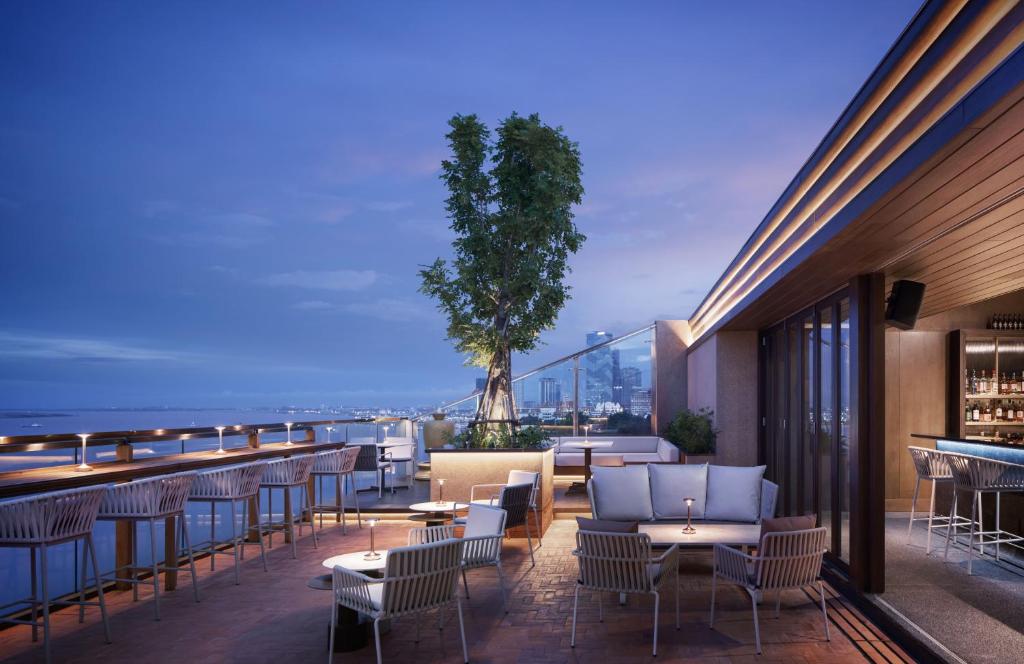 a rooftop bar with chairs and tables and a tree at Hotel KVL in Phnom Penh