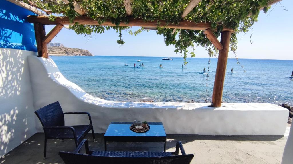 a table and chairs in front of the ocean at Stegna Rita's apartment in Archangelos