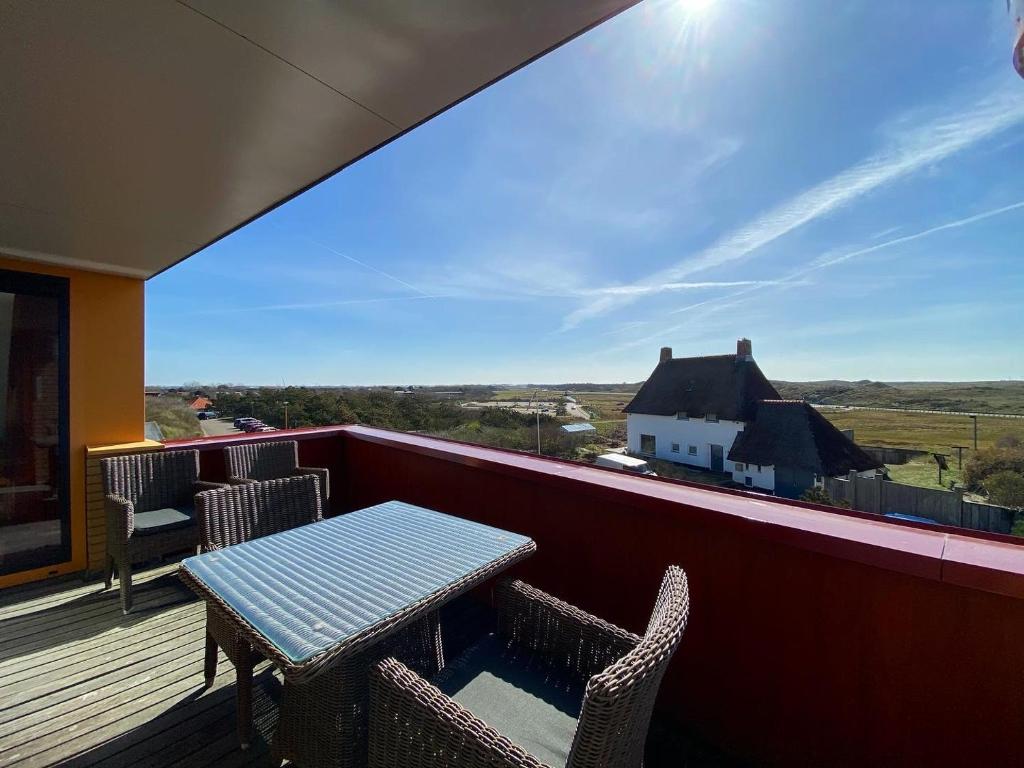a table and chairs on a balcony with a view of a house at Callantsoger Staete A305 in Callantsoog