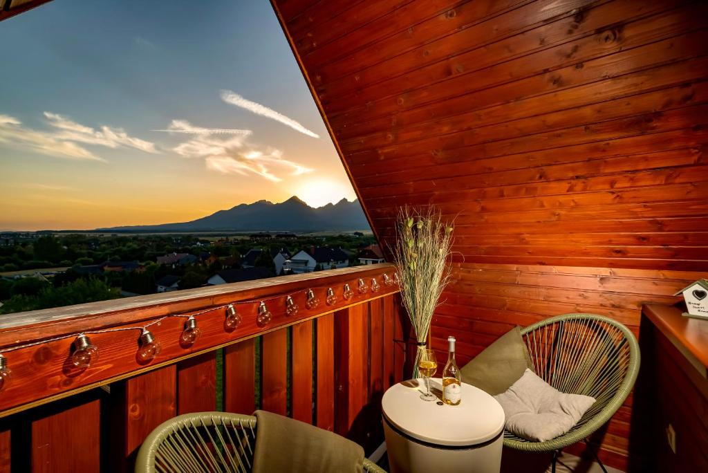 balcone con tavolo, sedie e tramonto di TATRYSTAY Cactus Cozy II Apartment Tatry view a Veľká Lomnica