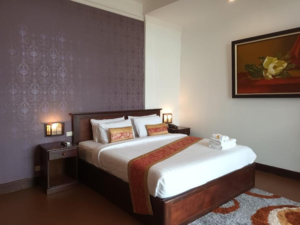 una camera da letto con un letto e un dipinto sul muro di Seasons Riverside Hotel a Vientiane