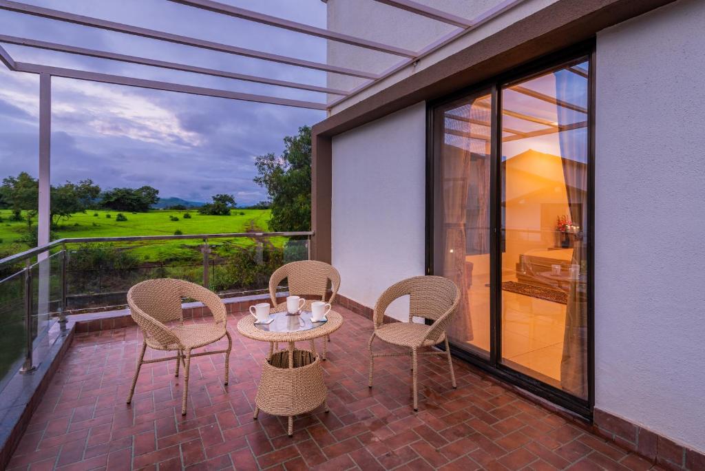 un patio con tavolo e sedie sul balcone. di SaffronStays Aster, plunge pool villa with garden, Lonavala a Lonavala