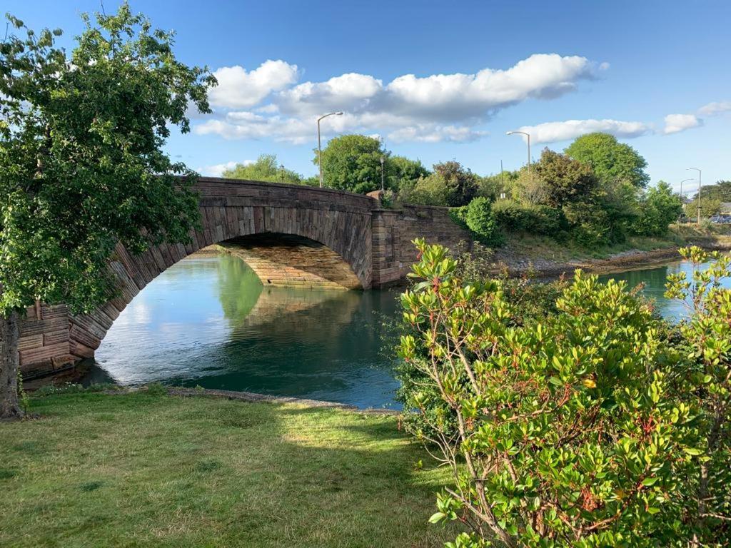 a stone bridge over a river in a park at Town centre one bed apartment in Dungarvan