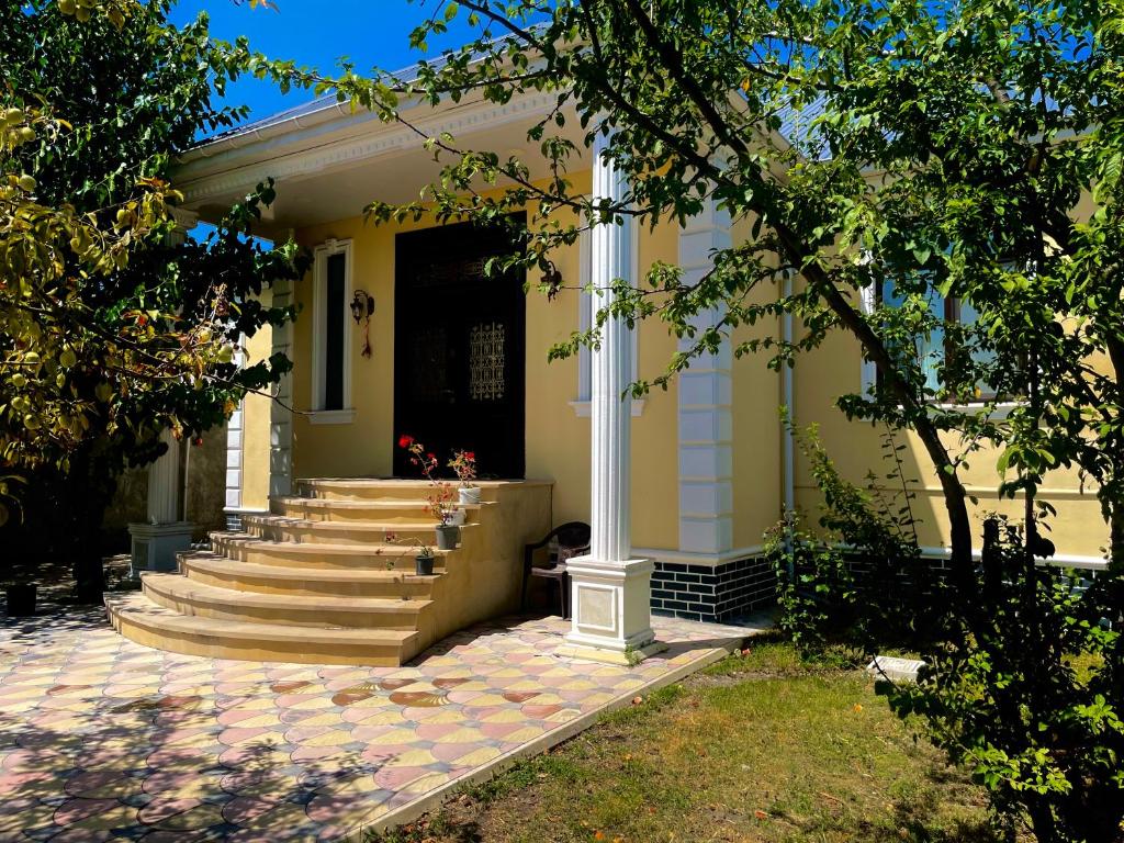 a yellow house with stairs and a black door at EMIREST Villa in Gabala