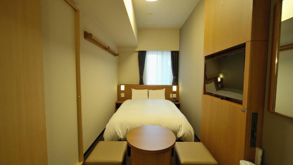 a small room with a bed and a television at Dormy Inn Akihabara in Tokyo