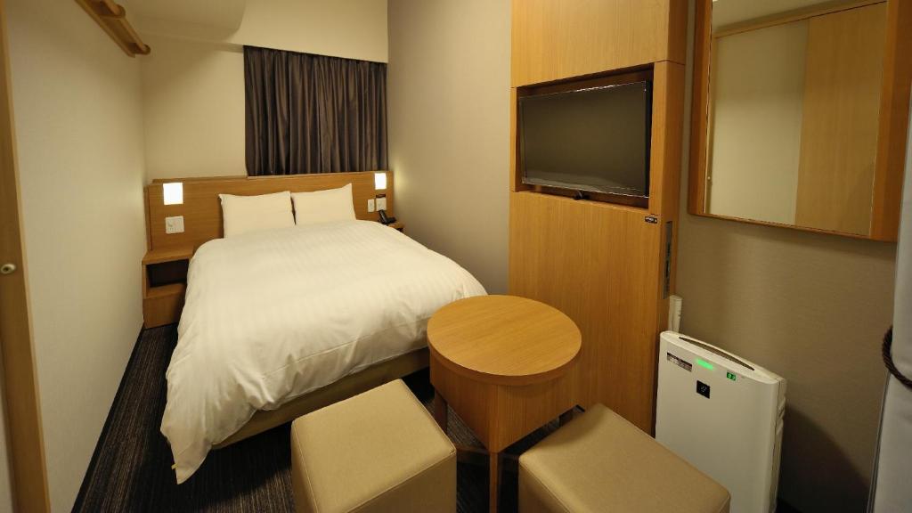 a small room with a bed and a television at Dormy Inn Akihabara in Tokyo