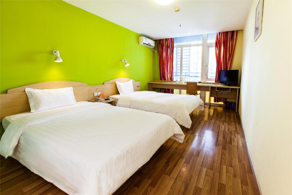 two beds in a room with a green wall at 7Days Inn Xi'an Big Wild Goose Pagoda Shanbo Branch in Xi'an