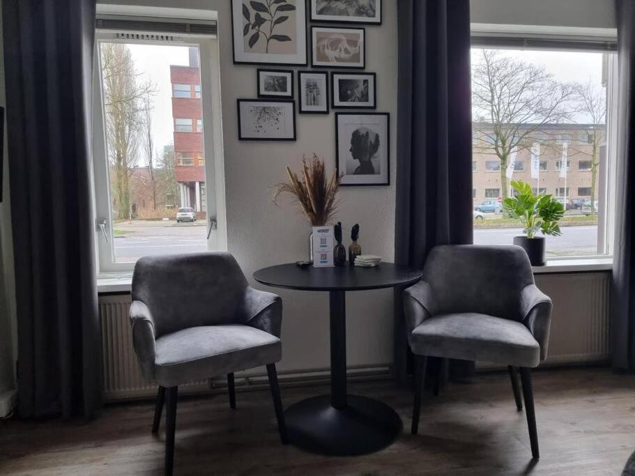 a table and two chairs in a room with two windows at Studio Trenz - stylish duo studio in Groningen