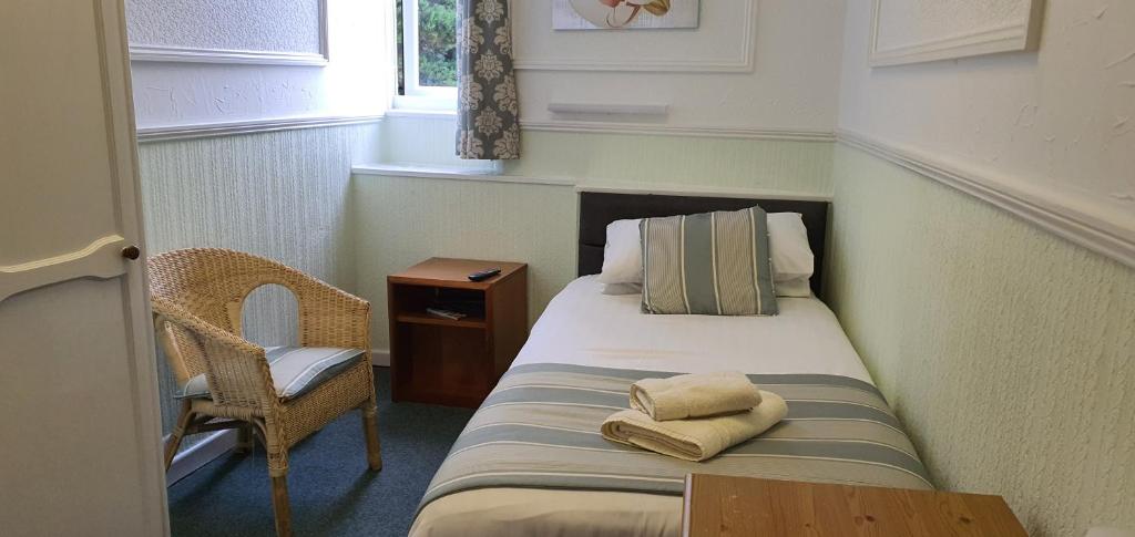a small room with a bed and a chair at CORBIERE GUEST HOUSE in Weston-super-Mare