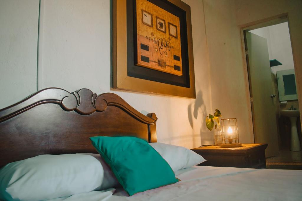 a bed with a wooden headboard and a green pillow at La Casa del K&eacute;ej Hostel in M&eacute;rida
