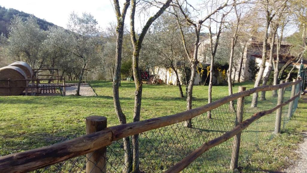 einen Holzzaun vor einem Feld mit Bäumen in der Unterkunft Charming 4-Bed Cottage 15 minutes from Florence in Impruneta
