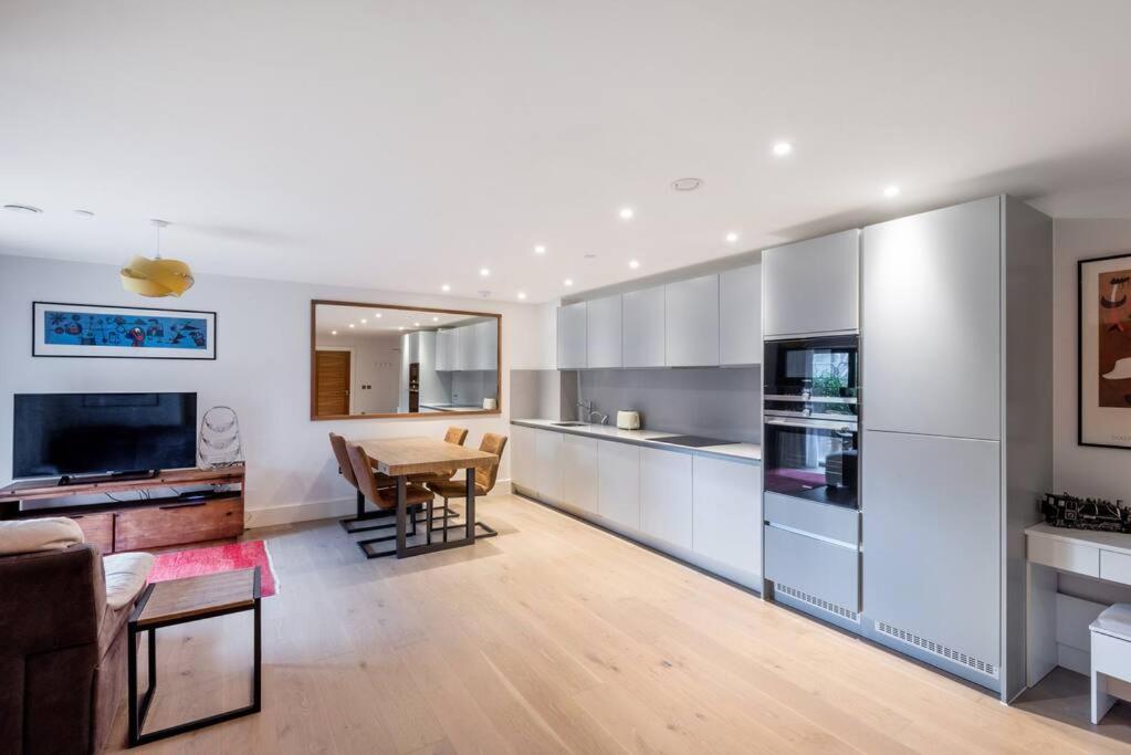 a kitchen with white cabinets and a dining room at STYLISH 2 BED 2 BATH IN HIGHGATE & FREE PARKING in London