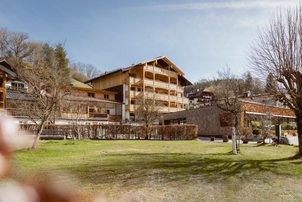 a large building in a park with trees in the foreground at Seehotel Berau in St. Wolfgang