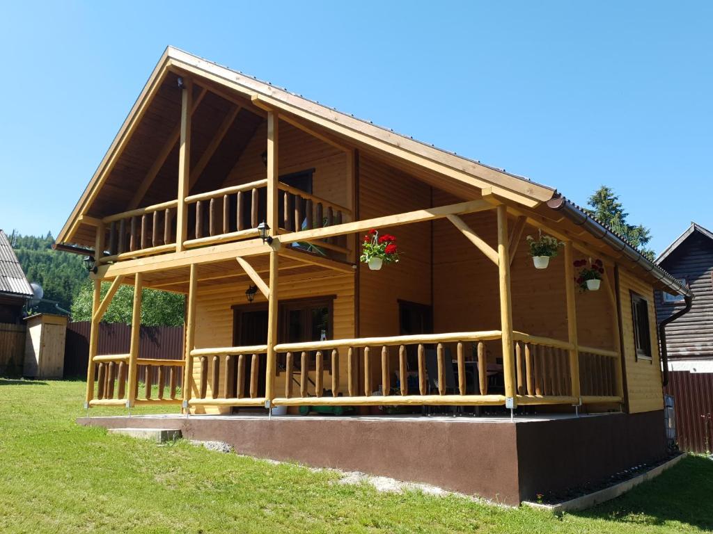 een groot houten huis met een groot terras bij Cabana DEMI in Gheorgheni