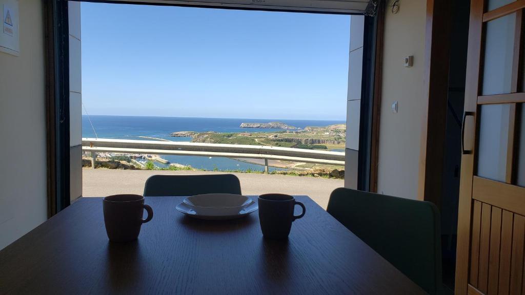 una mesa con dos tazas y vistas al océano en La Casuca de Rosi en Suances en Suances