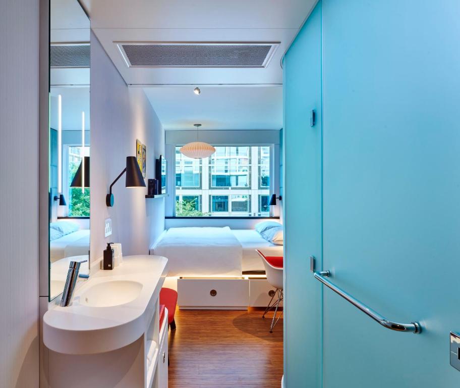 a bathroom with a sink and a bed in a room at citizenM Washington DC NoMa in Washington, D.C.