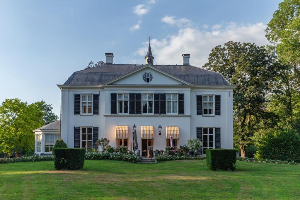 a large white house with a large yard at De Heerlijkheid Loenen Bed en Breakfast in Slijk-Ewijk