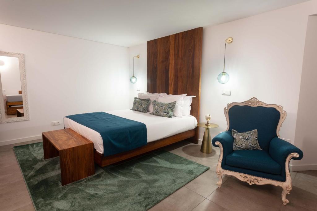 a bedroom with a bed and a blue chair at Casa dos Romeiros in Santa Bárbara