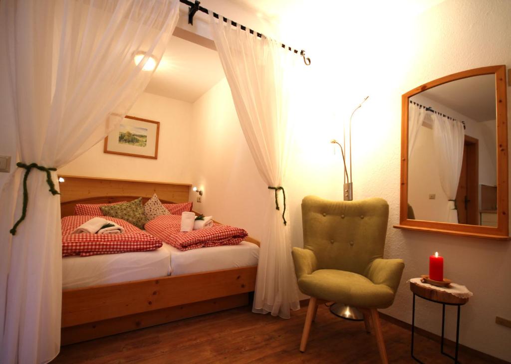 a bedroom with a bed and a chair and a mirror at AlmDorf Tonnerhütte in Mühlen