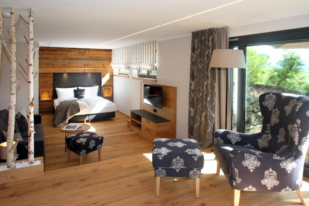 a bedroom with a bed and a tv and chairs at Bergzauber Wohlfühlchalets in Bolsterlang