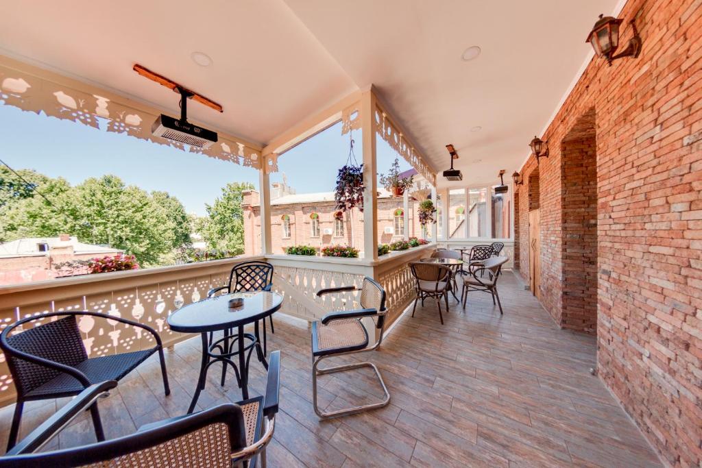een balkon met tafels en stoelen en een bakstenen muur bij Sina Hotel in Tbilisi City