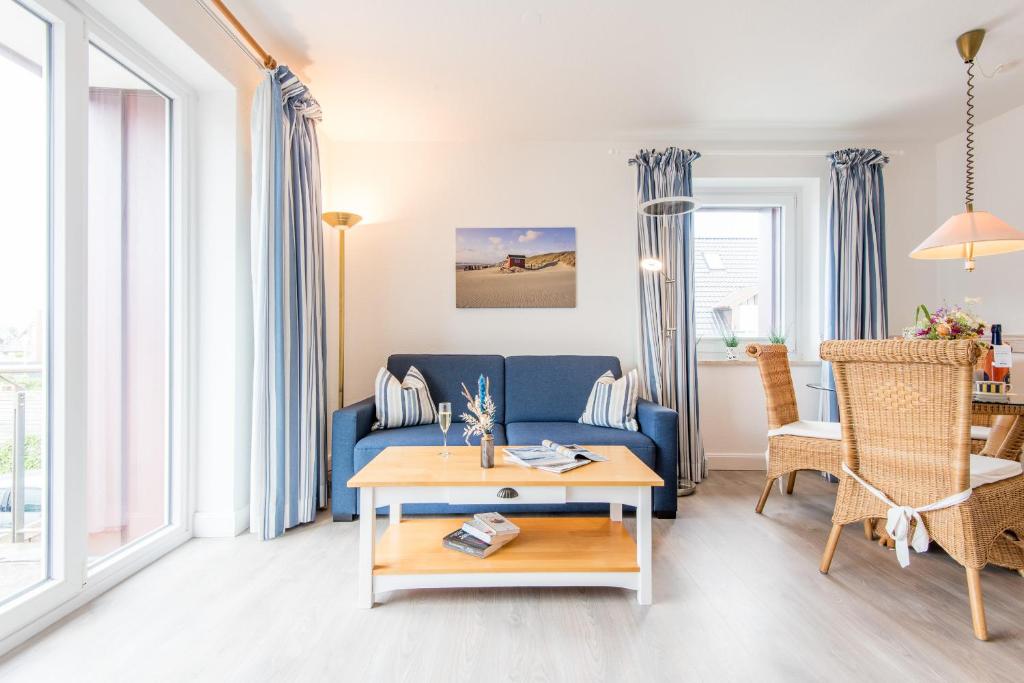 - un salon avec un canapé bleu et une table dans l'établissement Haus Hauke Whg 8, à Westerland