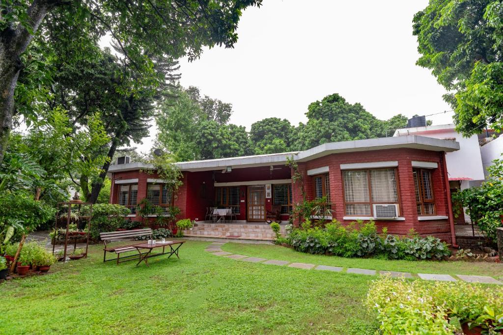 a red house with a picnic table in the yard at SaffronStays Doon Garden Villa - near Doon School and Mall Road in Dehradun