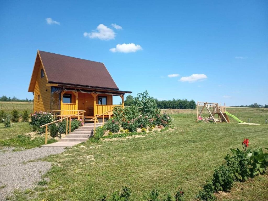 ein Haus auf einem Feld mit Spielplatz in der Unterkunft Domek na Wsi in Bodzentyn