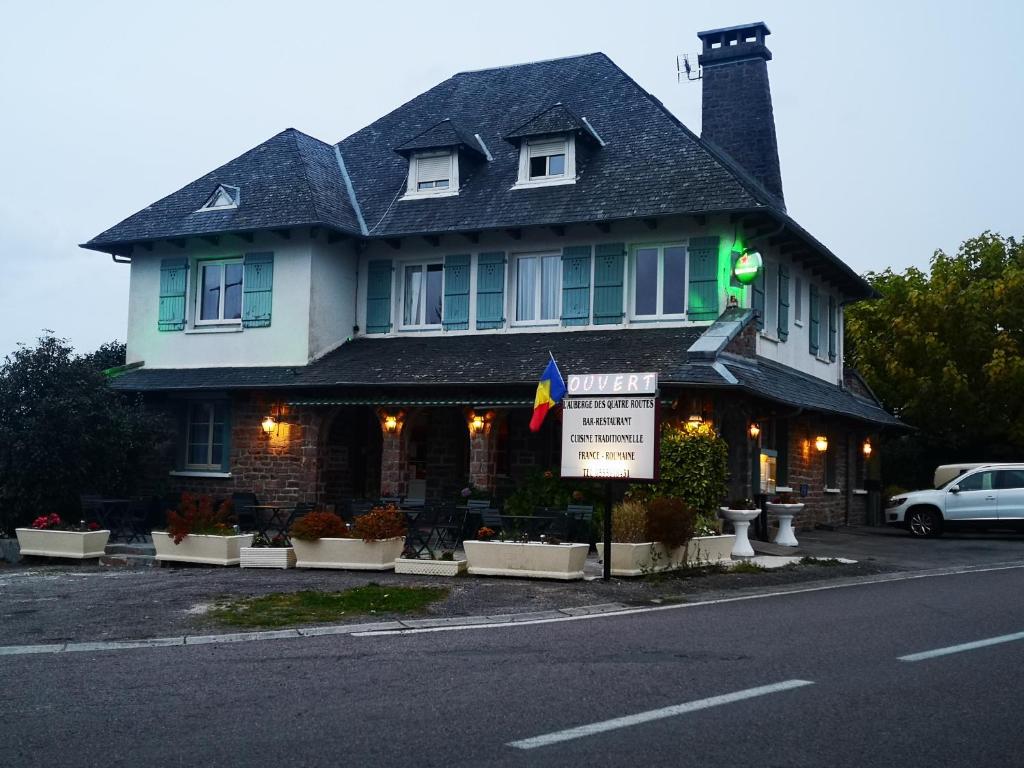 une maison avec un panneau devant elle dans l'établissement L'auberge des quatre routes, à Albussac