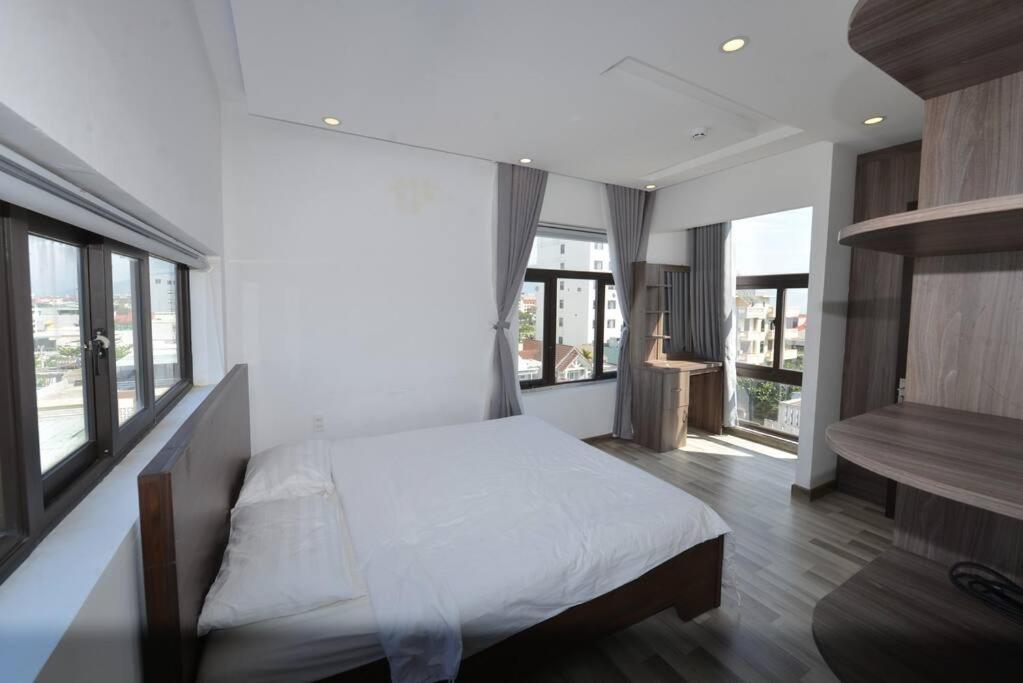 a bedroom with a bed with white sheets and windows at Two-Bedrooms - POOL SEA VIEW - 6A - BLUE SEA APARTMENT in Da Nang