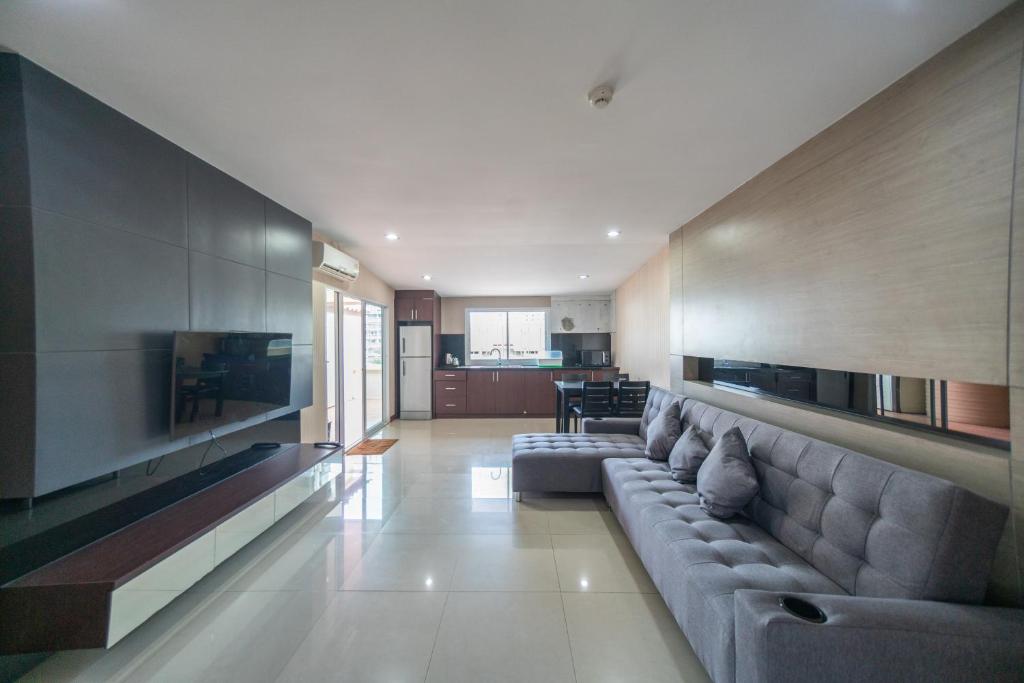 a living room with a large couch and a television at Shiba Guesthouse in Pattaya South