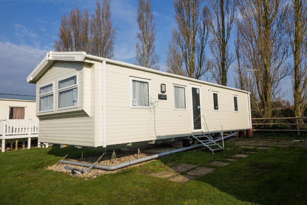 a white mobile home sitting in a yard at Lovely 6 Berth Caravan At Coopers Beach Park In Essex Ref 49075p in East Mersea